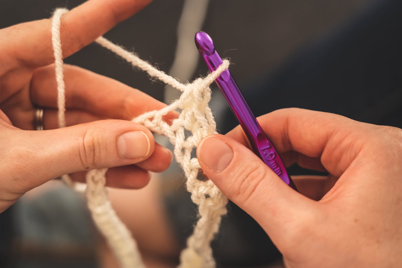 Learn Crochet Easily for Beginners Hands crocheting with a purple hook, showcasing intricate yarn details.